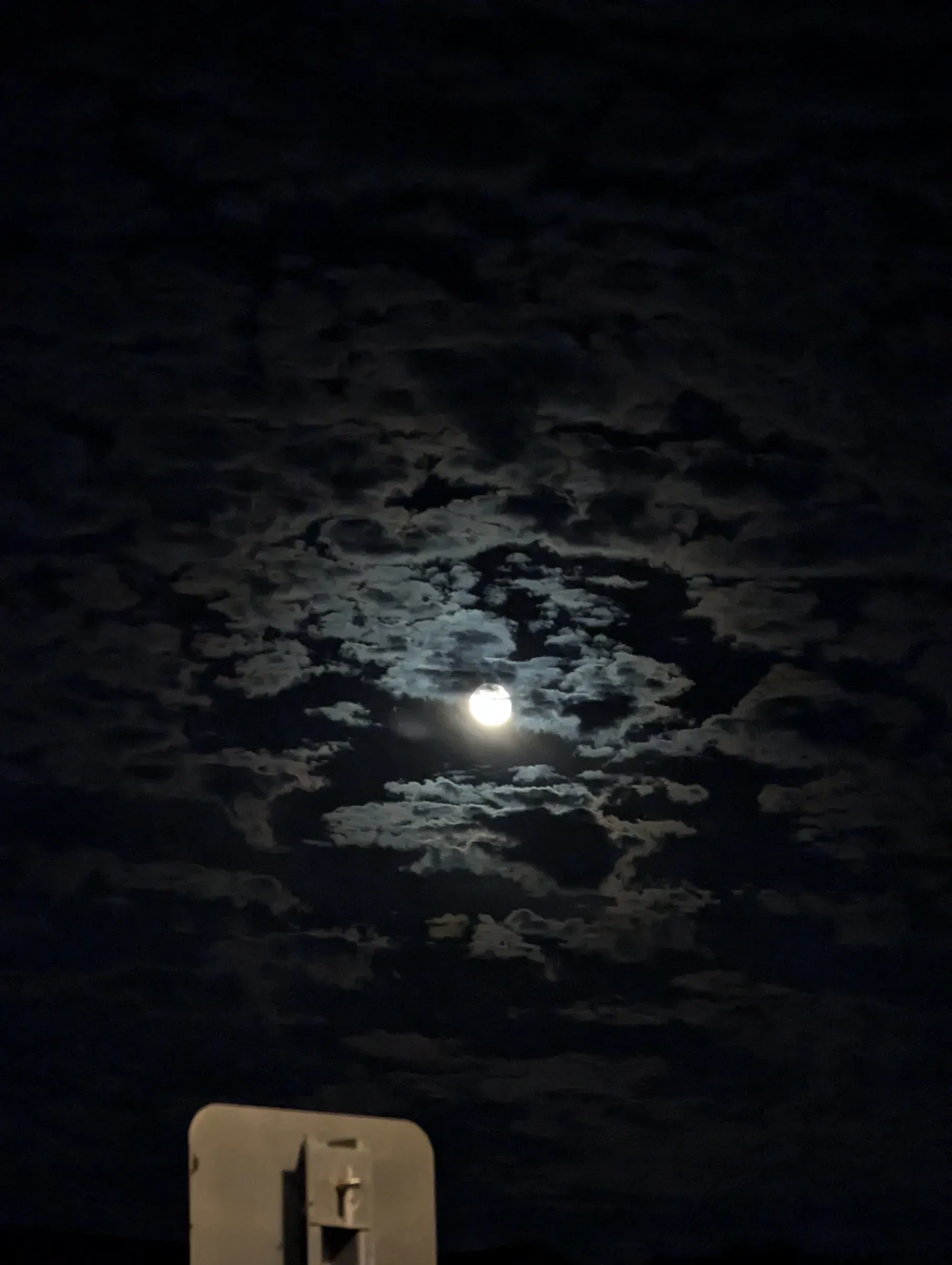 The moon glowing through broken clouds in a dark night sky